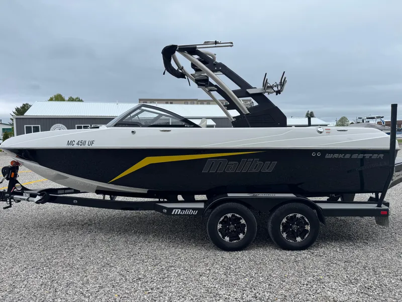 Slide: The Image of 2018 Malibu VLX boat on trailer, black and white design, parked outdoors. - 5