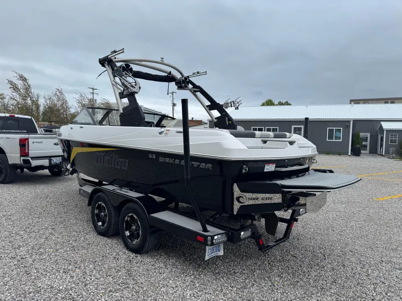 Slide: The Image of 2018 Malibu VLX boat on trailer, parked on gravel, with overcast sky. - 6