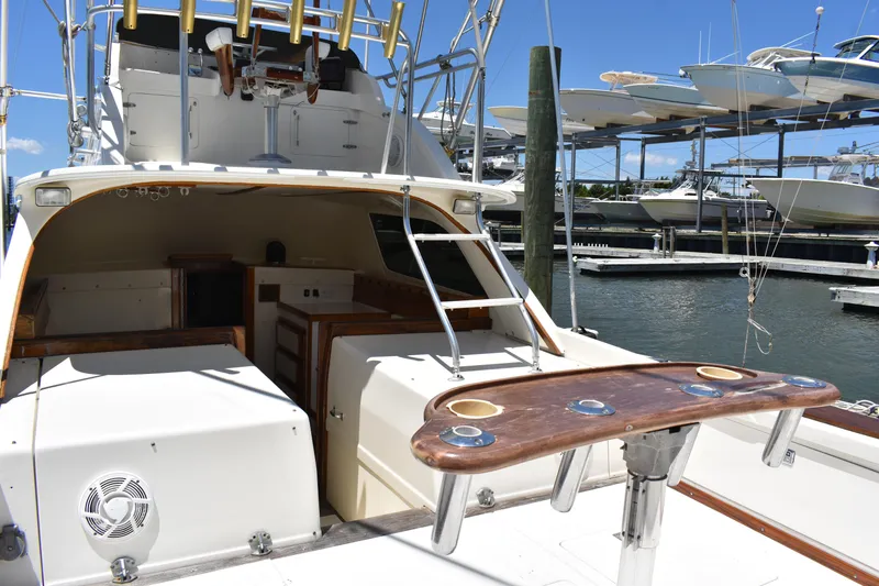 Slide: The Image of 1965 Bertram 31 boat with fishing setup, docked at marina under clear blue sky. - 12