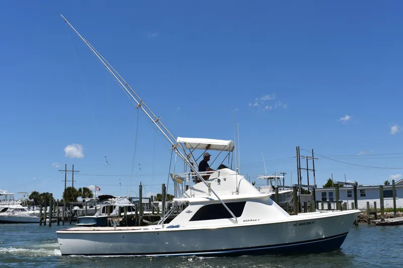 Slide: The Image of 1965 Bertram 31 boat cruising in a marina under a clear blue sky. - 5
