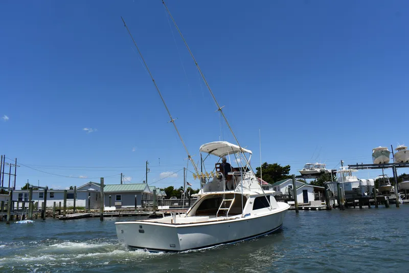 Slide: The Image of 1965 Bertram 31 boat cruising in a marina under a clear blue sky. - 6