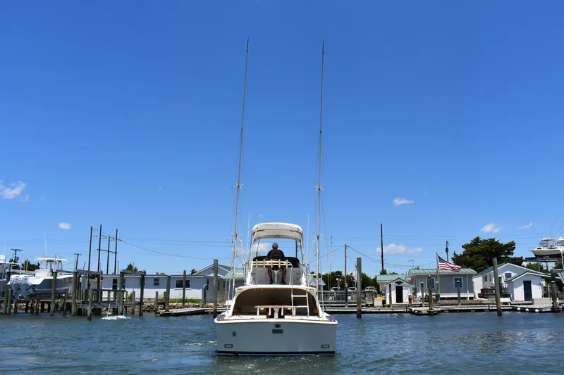 Slide: The Image of 1965 Bertram 31 boat on water near docks under clear blue sky. - 7