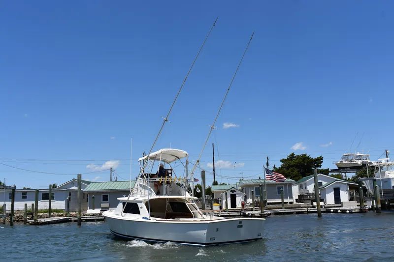 Slide: The Image of 1965 Bertram 31 boat docked at a marina under a clear blue sky. - 8
