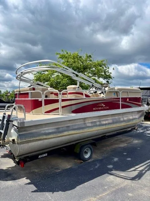 Slide: The Image of 2011 Bennington 20SLi pontoon boat with red accents, parked outdoors under cloudy skies. - 4