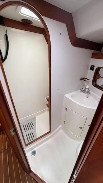 Slide: The Image of 2003 J Boats J/46 yacht bathroom with shower, sink, and wooden accents. - 49