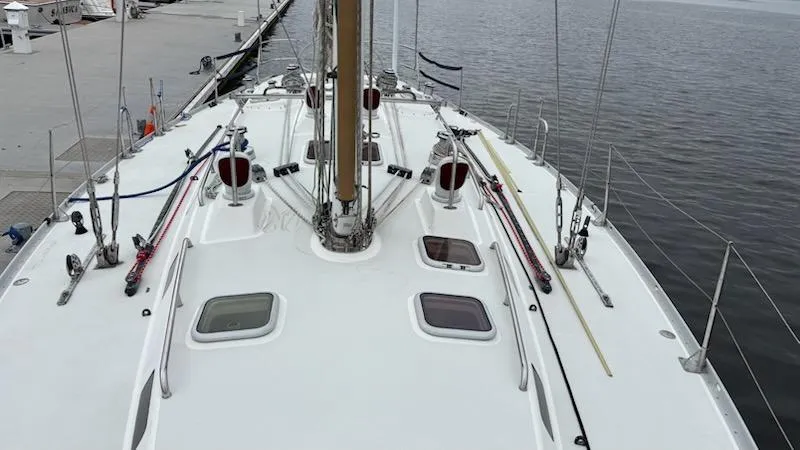 Slide: The Image of 2003 J Boats J/46 sailboat deck with rigging and hatches, docked by the water. - 9