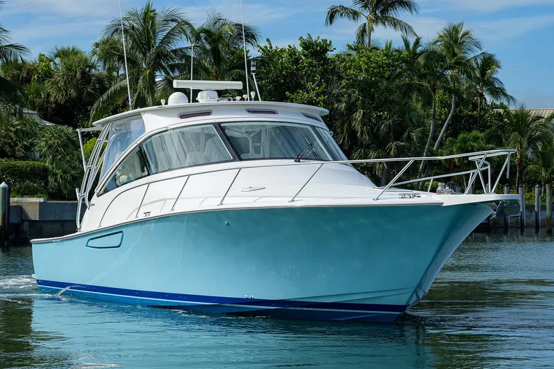 Slide: The Image of 2013 Viking 42 Open yacht cruising on calm waters with lush greenery background. - 29