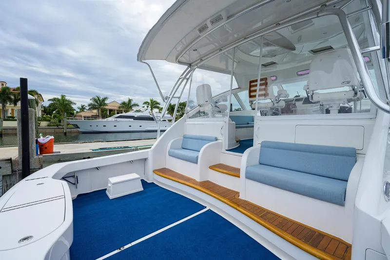 Slide: The Image of 2013 Viking 42 Open yacht with blue seating and wooden accents, docked near waterfront homes. - 5