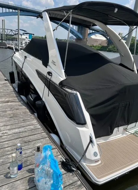 Slide: The Image of 2024 Regal 26 X boat docked by a river with bridge in background. - 1