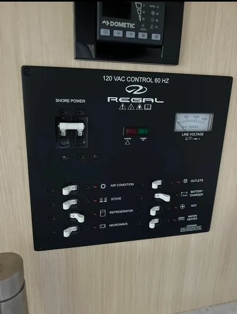 Slide: The Image of 2024 Regal 26 X control panel with switches for air conditioning, stove, refrigerator, and microwave. - 11