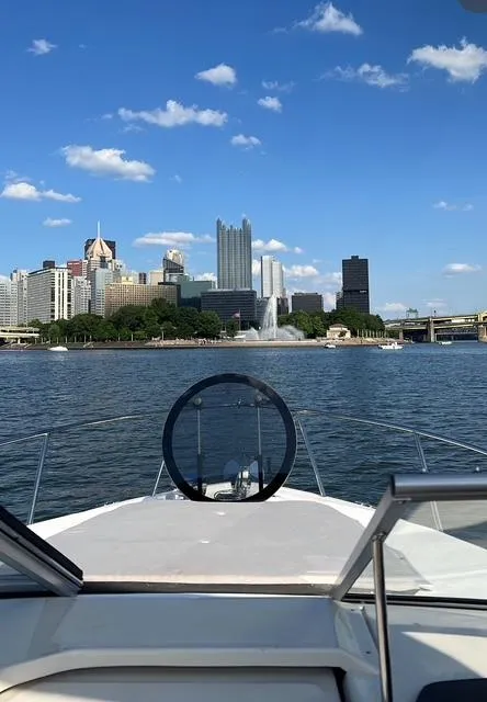 Slide: The Image of 2024 Regal 26 X boat cruising towards city skyline under blue sky. - 14