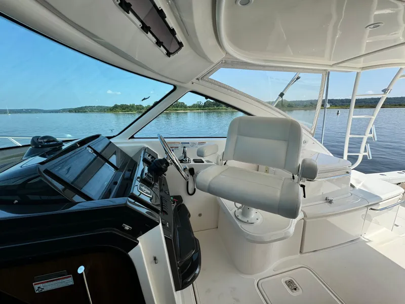 Slide: The Image of Cockpit view of 2019 Tiara Yachts 4300 Open, featuring helm and seating, on a serene lake. - 14