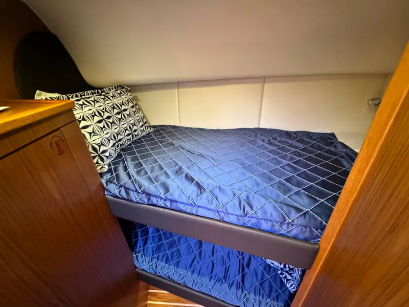 Slide: The Image of Cabin interior of 2019 Tiara Yachts 4300 Open with blue bedding and wooden accents. - 24