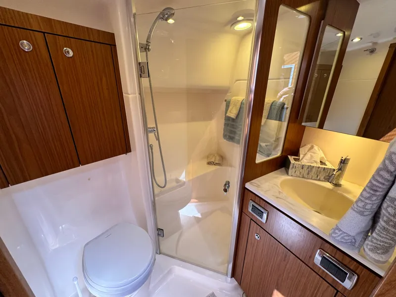 Slide: The Image of Bathroom interior of 2019 Tiara Yachts 4300 Open, featuring shower, sink, and wooden cabinetry. - 25