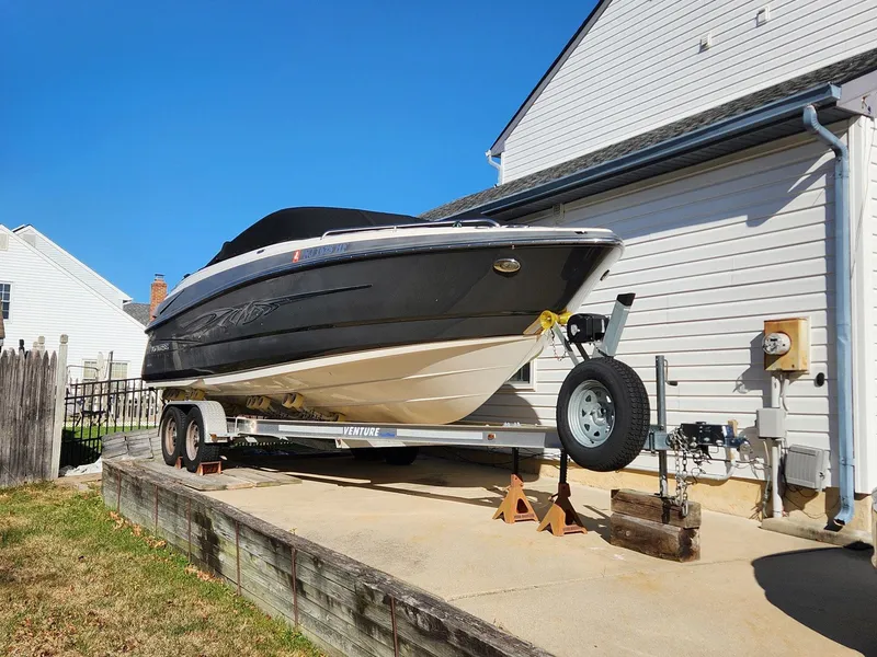 Slide: The Image of 2013 Monterey 264FSX boat on trailer beside house under clear blue sky. - 1