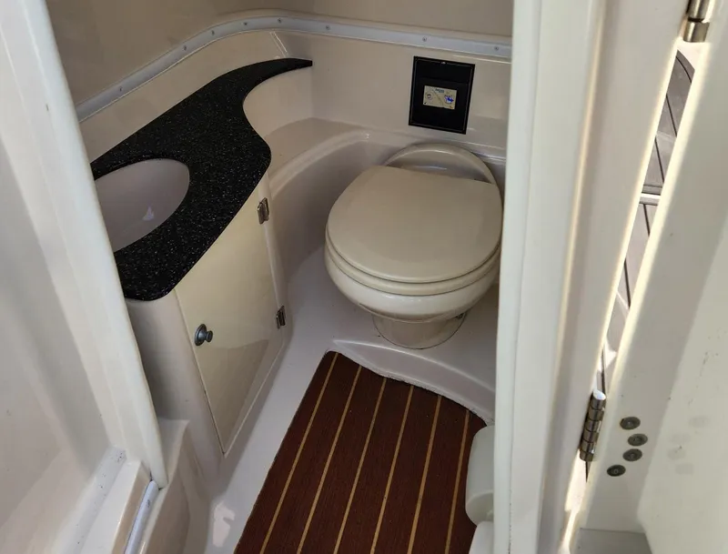 Slide: The Image of 2013 Monterey 264FSX boat bathroom with toilet, sink, and wood-patterned floor. - 5