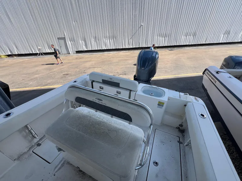 Slide: The Image of 2023 Cobia 237 Center Console boat with outboard motor, docked near a large building. - 13
