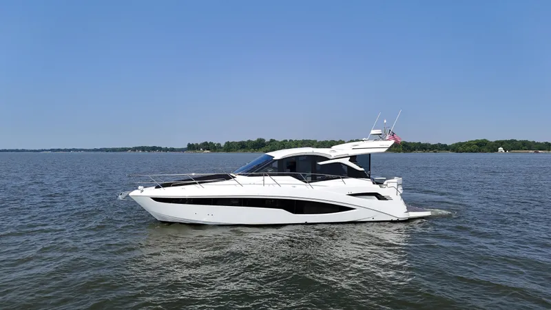 The Image of 2021 Galeon 425 HTS yacht cruising on a calm lake under a clear blue sky. - 0
