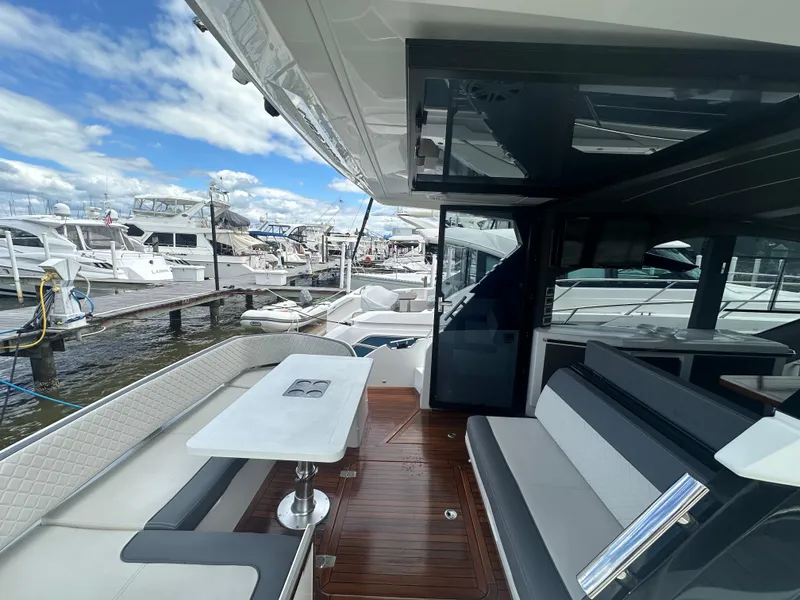 Slide: The Image of 2021 Galeon 425 HTS yacht interior with sleek seating and table, docked at marina. - 16