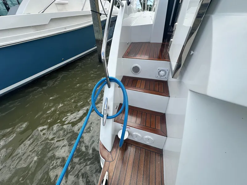 Slide: The Image of 2021 Galeon 425 HTS yacht with wooden steps and blue rope by the water. - 21