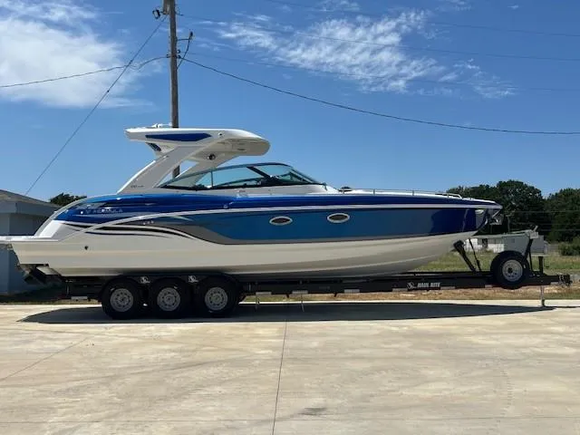 Slide: The Image of 2025 Formula 330 Crossover Bowrider I/O on trailer, blue and white design, parked outdoors. - 15