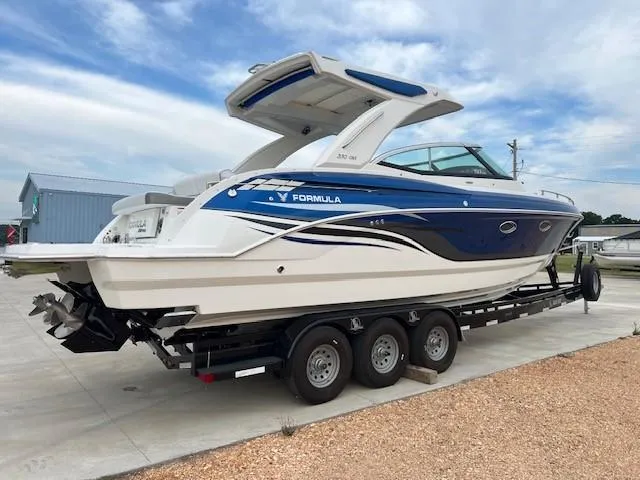 Slide: The Image of 2025 Formula 330 Crossover Bowrider I/O boat on trailer, blue and white design. - 4