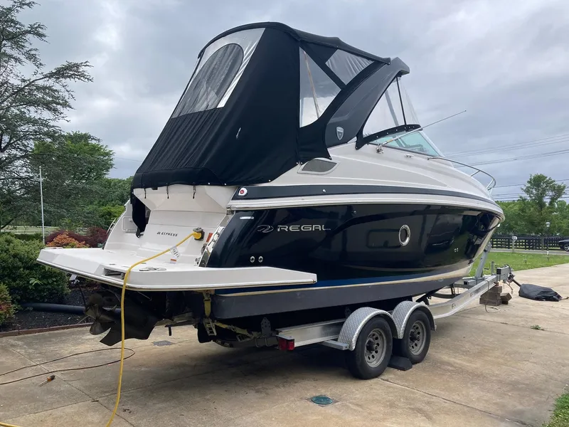 Slide: The Image of 2015 Regal 28 Express boat on trailer, black canopy, parked outdoors. - 1