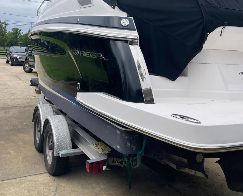 Slide: The Image of 2015 Regal 28 Express boat on trailer, black and white exterior, parked outdoors. - 15