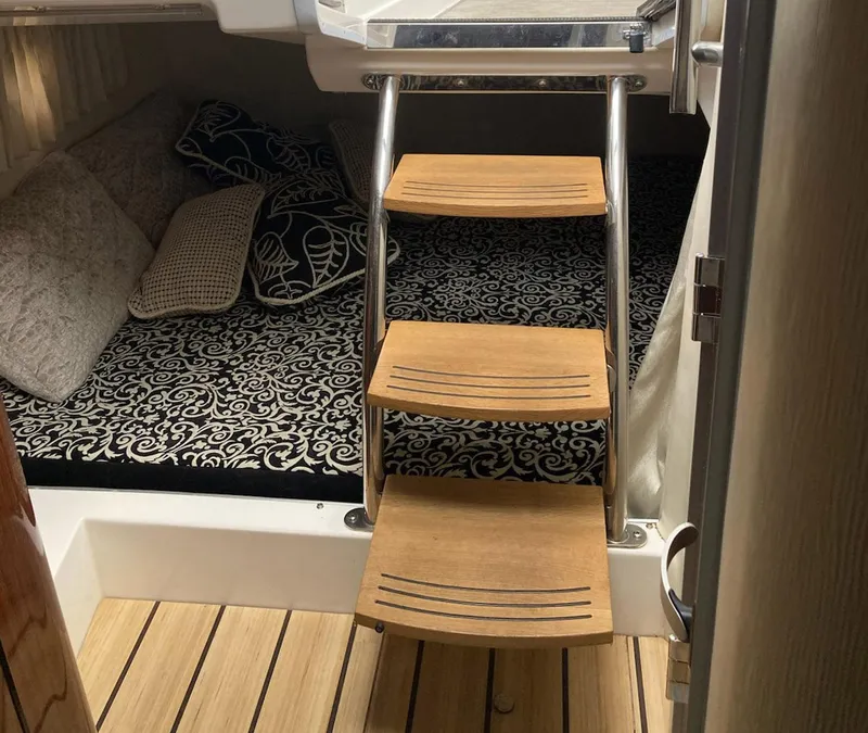 Slide: The Image of Interior of 2015 Regal 28 Express boat with wooden steps and patterned bedding. - 5