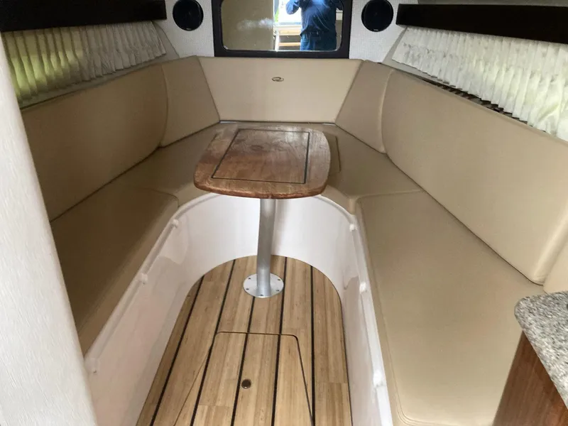 Slide: The Image of Interior of 2015 Regal 28 Express boat with beige seating and wooden table. - 6