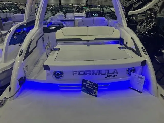 Slide: The Image of 2025 Formula 310 Bowrider I/O with illuminated seating and sleek design at a boat show. - 11