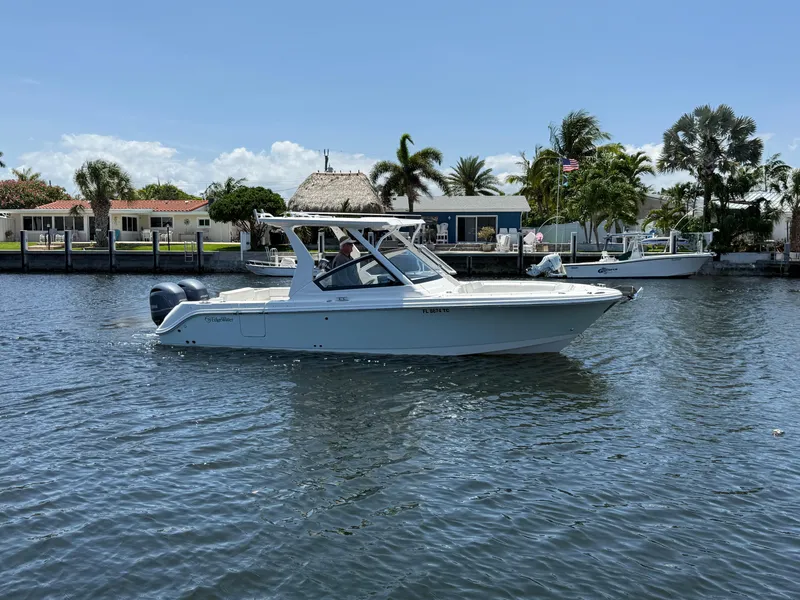 Slide: The Image of 2022 Edgewater 262 CX boat cruising on a sunny day near waterfront homes. - 0