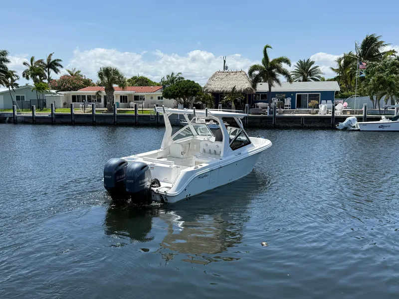 Slide: The Image of 2022 Edgewater 262 CX boat cruising on a sunny waterfront with palm trees. - 1