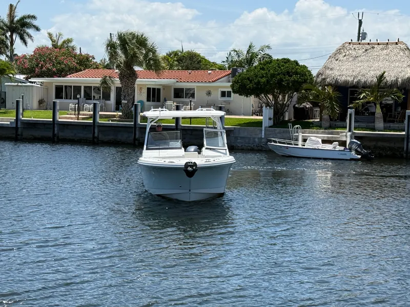 Slide: The Image of Edgewater 262 CX 2022 boat cruising on a sunny waterfront near residential homes. - 10