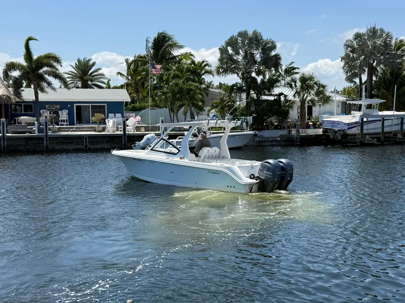 Slide: The Image of 2022 Edgewater 262 CX boat cruising on a sunny waterfront with palm trees. - 11
