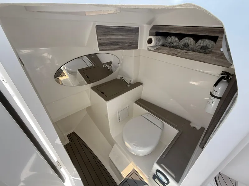 Slide: The Image of 2022 Edgewater 262 CX boat bathroom with toilet, sink, mirror, and storage shelves. - 18