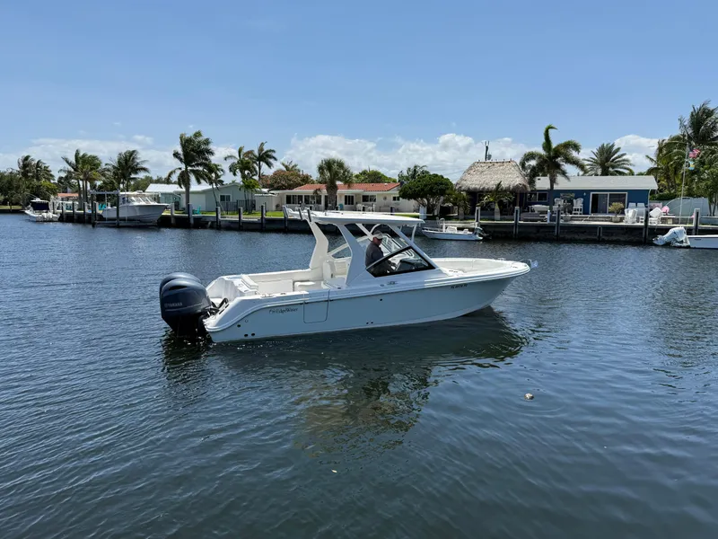 Slide: The Image of 2022 Edgewater 262 CX boat on a calm canal with palm trees and houses. - 2