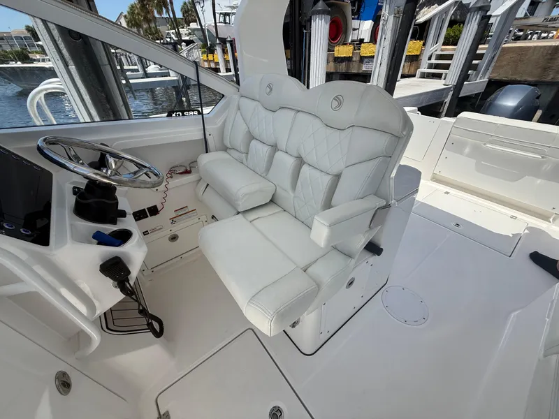Slide: The Image of 2022 Edgewater 262 CX boat interior with white seating and steering console. - 21
