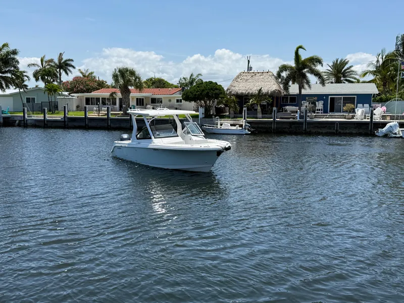 Slide: The Image of 2022 Edgewater 262 CX boat on a sunny waterfront with palm trees and houses. - 3