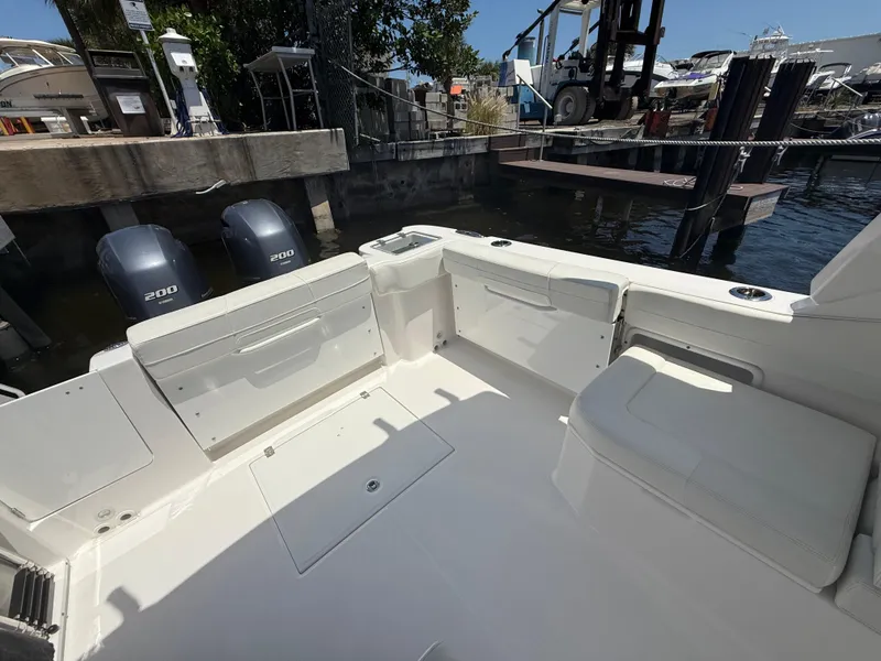 Slide: The Image of 2022 Edgewater 262 CX boat interior with seating and twin 300 engines at a marina. - 34