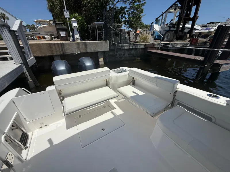 Slide: The Image of 2022 Edgewater 262 CX boat interior with seating and dual engines at a dock. - 35