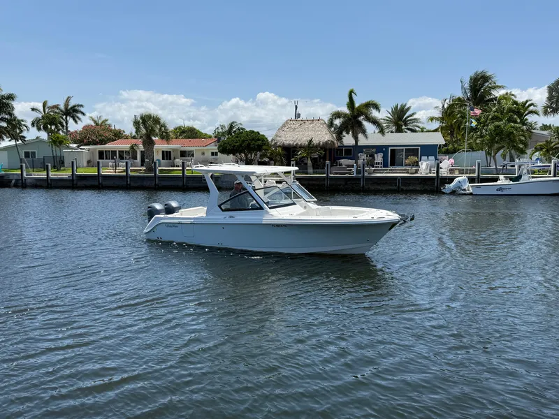 Slide: The Image of 2022 Edgewater 262 CX boat cruising on a sunny day near waterfront homes. - 4