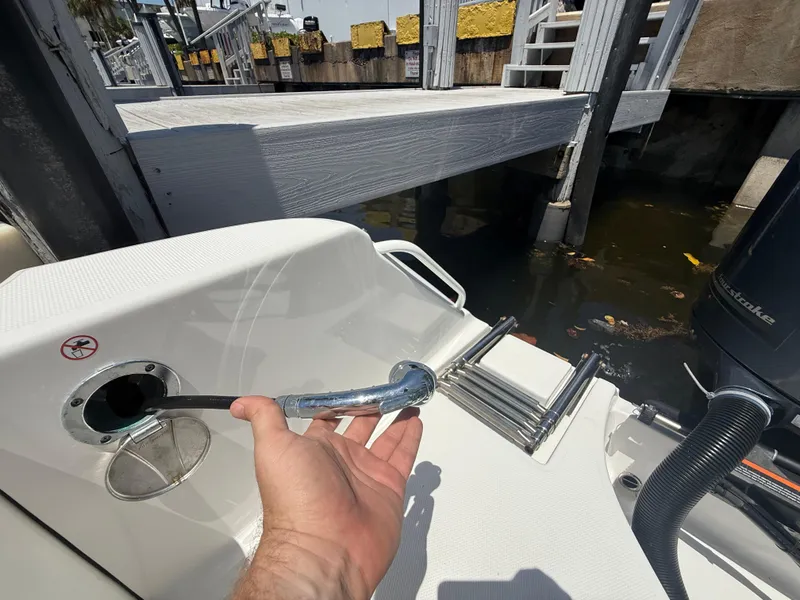 Slide: The Image of Hand holding a hose on a 2022 Edgewater 262 CX boat near a dock. - 49