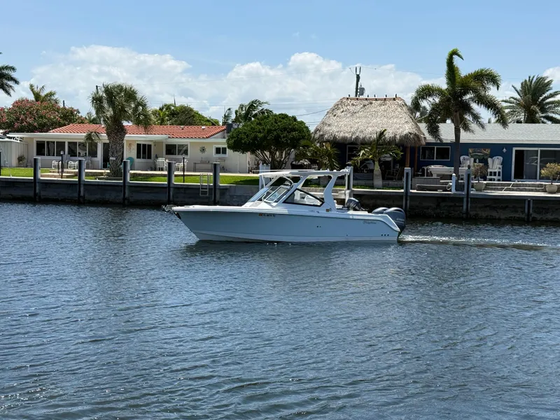 Slide: The Image of 2022 Edgewater 262 CX boat cruising on a sunny waterfront with palm trees. - 5