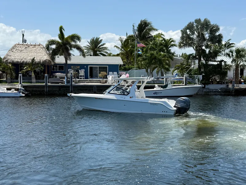 Slide: The Image of 2022 Edgewater 262 CX boat cruising on a sunny waterfront with palm trees. - 8