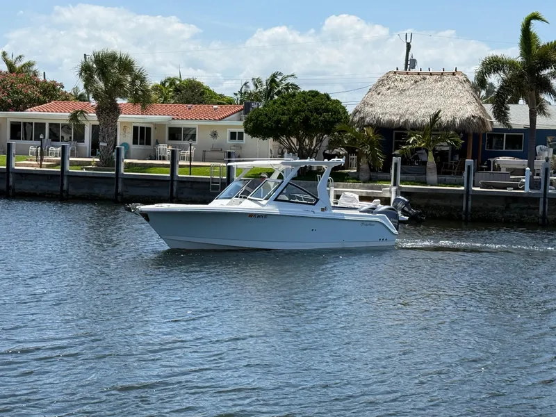 Slide: The Image of 2022 Edgewater 262 CX boat cruising on a sunny waterfront with palm trees. - 9