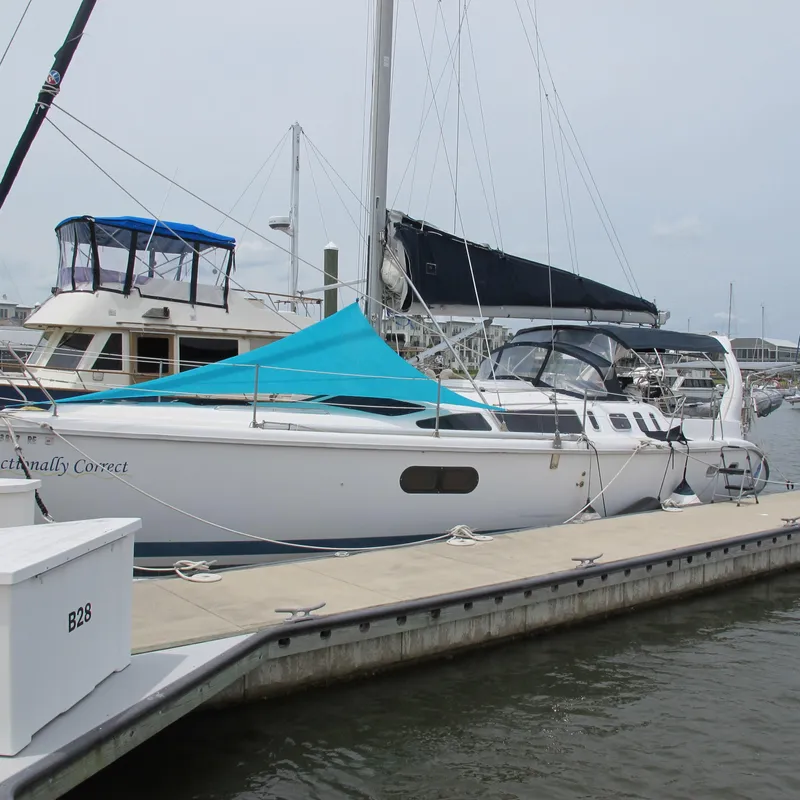 Slide: The Image of 1998 Hunter 410 sailboat docked at marina with blue canopy and black sail cover. - 2
