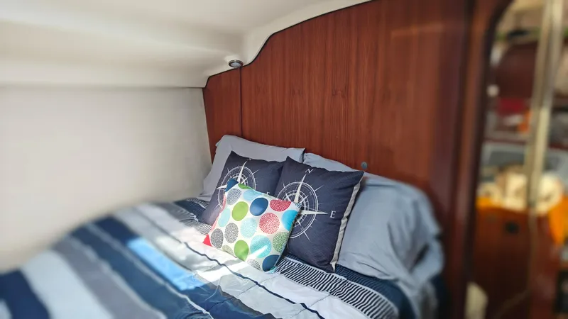 Slide: The Image of Cozy cabin bedroom in 1998 Hunter 410 sailboat with striped bedding and decorative pillows. - 26