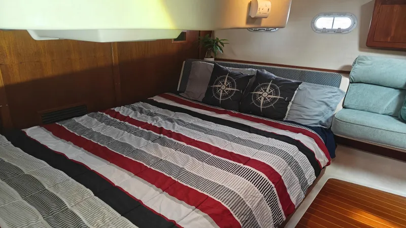 Slide: The Image of Cozy cabin interior of 1998 Hunter 410 sailboat with striped bedding and nautical-themed pillows. - 48