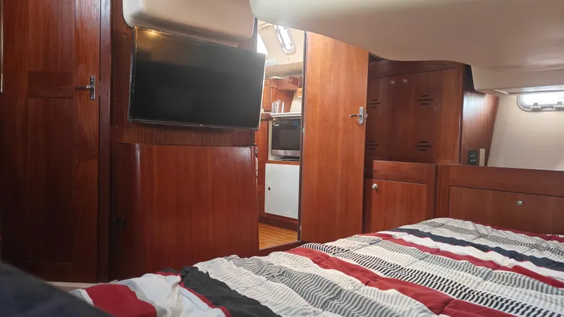 Slide: The Image of Interior of 1998 Hunter 410 yacht with wood paneling, bed, and TV. - 49
